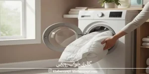 «شستشوی کالای خواب در ماشین لباسشویی؛ بیرون آوردن لحاف یا کاور تشک سفید از لباسشویی در محیط روشن و تمیز»